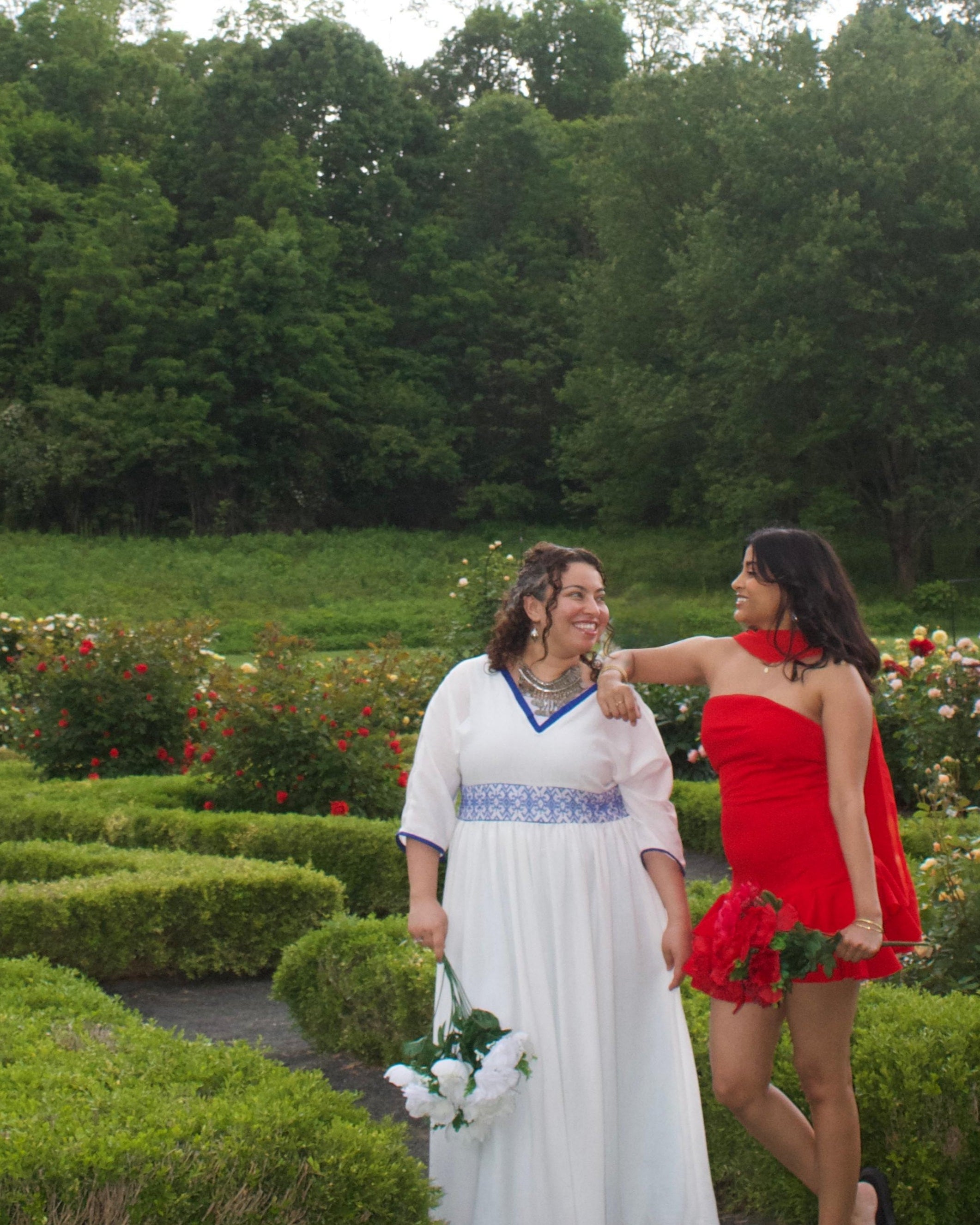 Two women standing in a garden with trees in the background